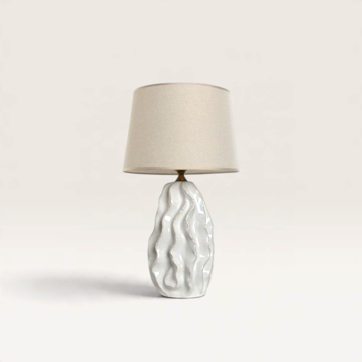 Vintage Industrial Gabun table lamp with a white porcelain wavy base and a neutral fabric drum shade.