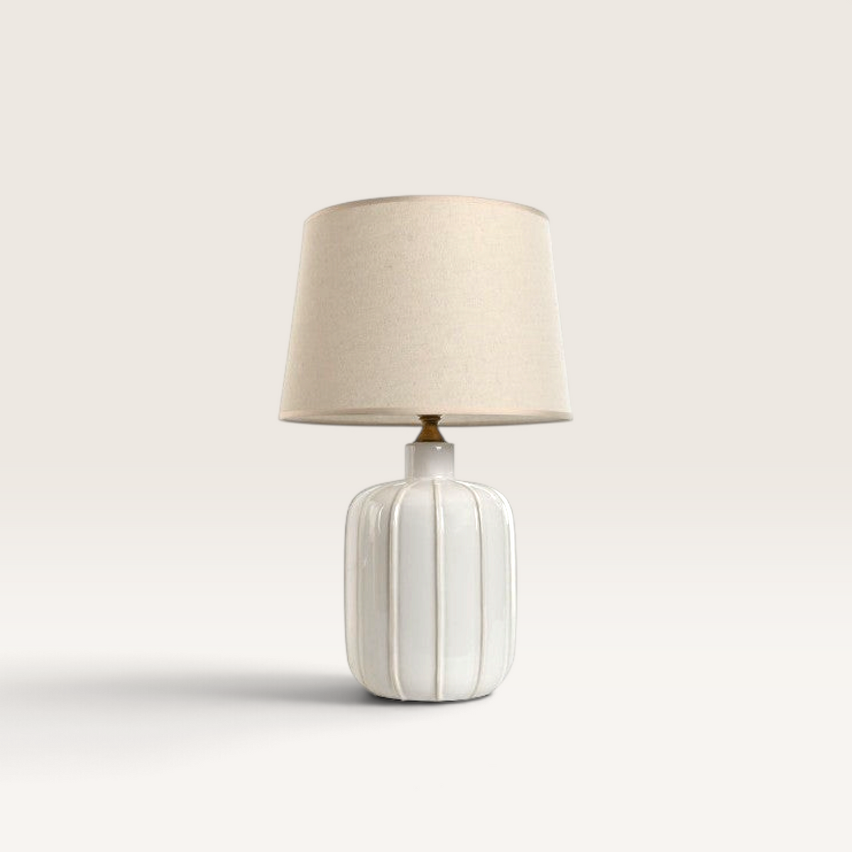 Vintage Industrial Lumi table lamp with a white ribbed ceramic base, brass accents, and a neutral fabric shade.